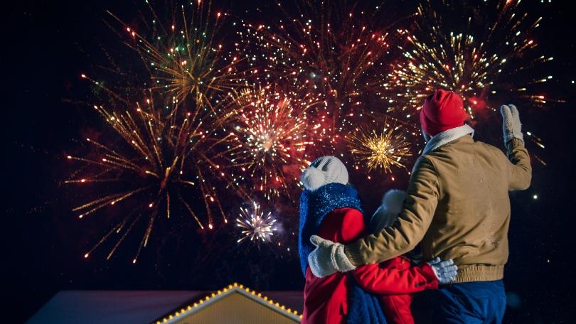 Eltern mit Kind sehen Feuerwerk zu - Silvester mit Kindern feiern