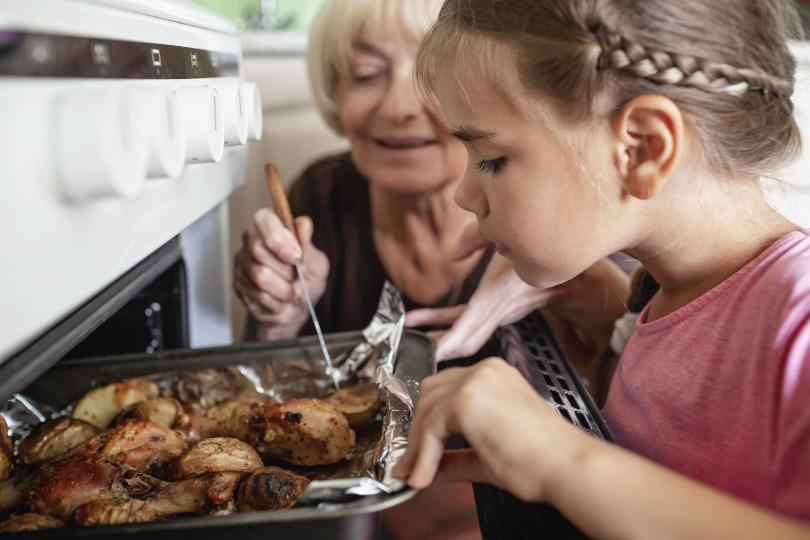Großmutter prüft mit Enkelin die Ofenkartoffeln