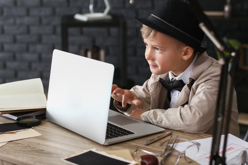 Junge in Detektiv-Outfit am Laptop - Silvester mit Kindern feiern