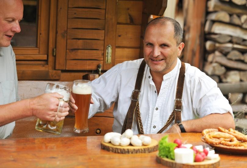2 Maenner machen Brotzeit und trinken Bier - Bayrische Brotzeitplatte 